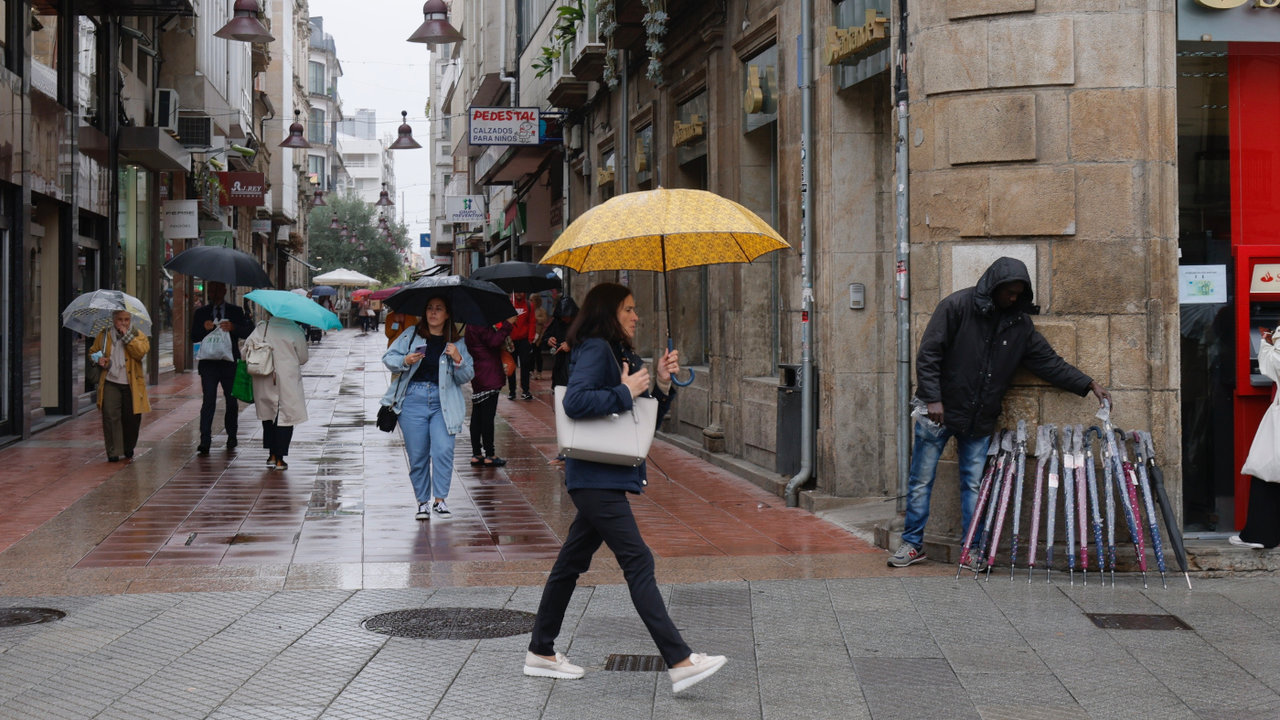 <p> Personas se protegen de la lluvia en Pontevedra. GONZALO GARCÍA </p>