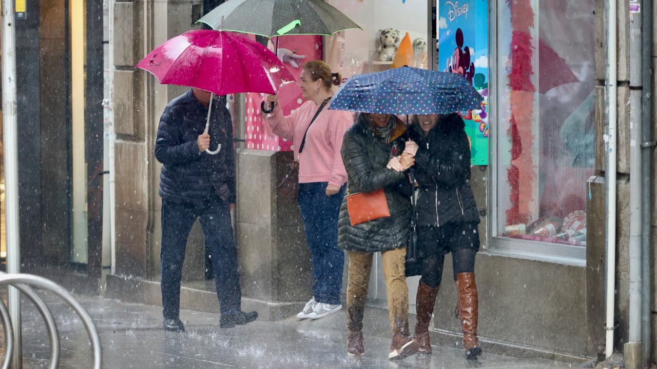 <p> Gente resguardándose de la lluvia bajo los paraguas en Pontevedra. RAFA FARIÑA </p>