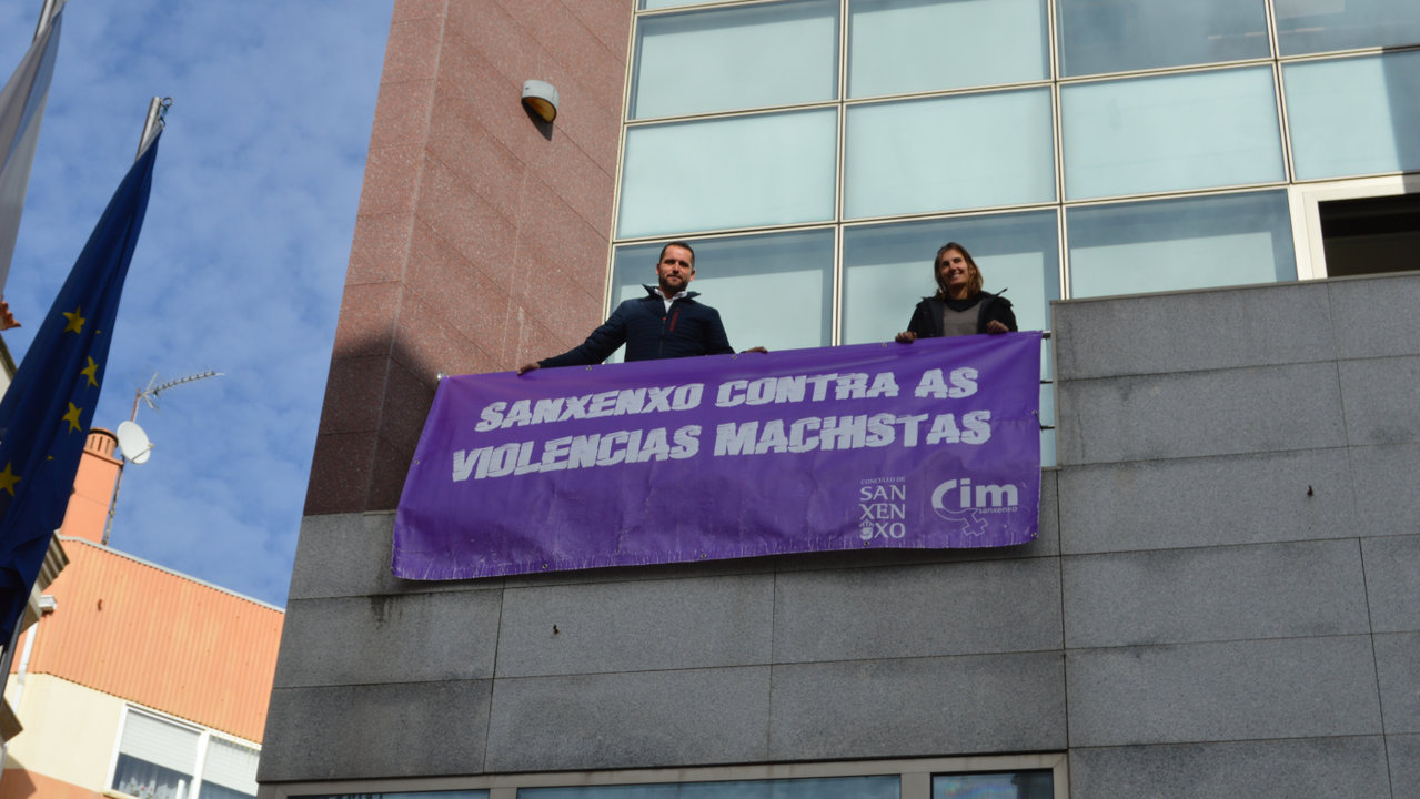 Los ediles Daniel Arosa y Flavia Besada, este miércoles durante el despliegue de la pancarta en la fachada del Concello. DS