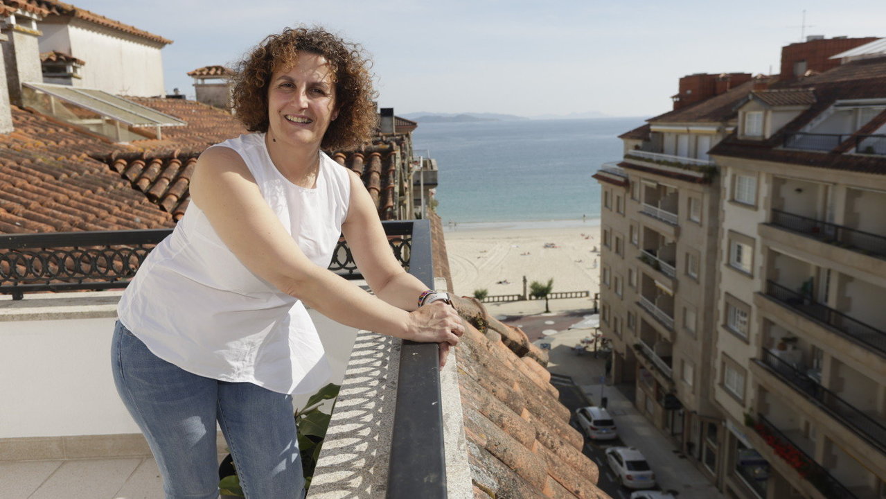 Dulcinea Aguín asomada a la terraza de uno de los pisos de Aviturga: un ático en Sanxenxo con la playa de Silgar al fondo. DAVID FREIRE